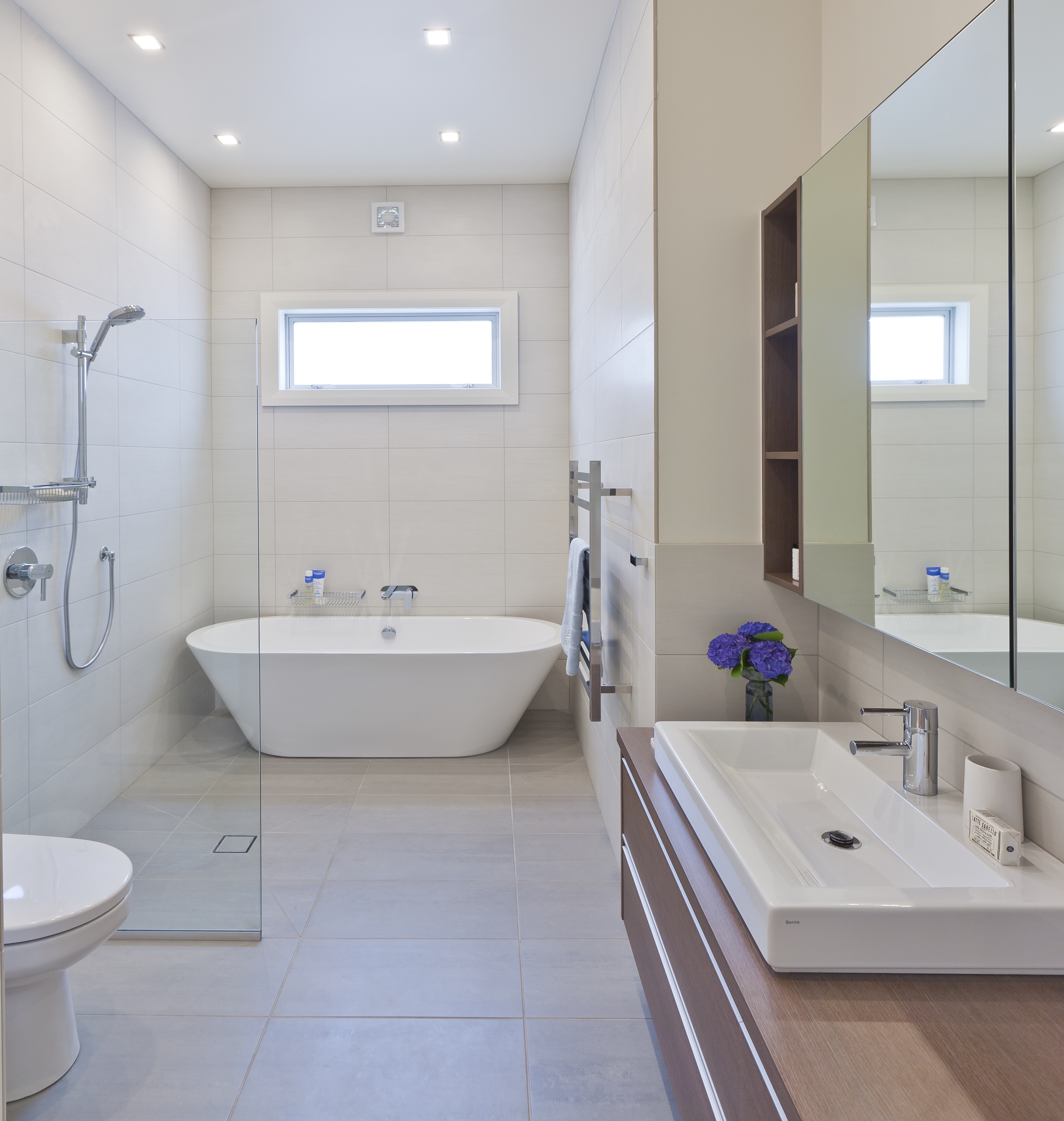 Keeping a bathroom floor clear of lips and steps, and cantilevering cabinetry off the wall, makes the whole room seem larger.
